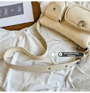 Detail of adjustable wide shoulder strap with metal eyelets on a cream utility handbag