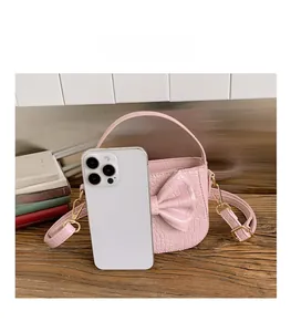 Detailed size comparison of a mini pink bow handbag next to a white smartphone