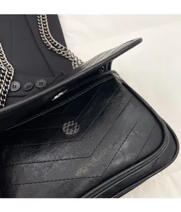 Detailed macro view of the silver magnetic buckle on a black quilted leather bag