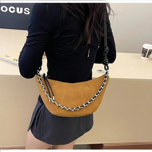 Detail of mustard yellow croissant bag featuring quilted segments and silver metal chain