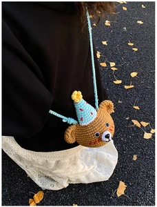 Detailed knit texture of a brown crochet bear crossbody bag with a blue party hat