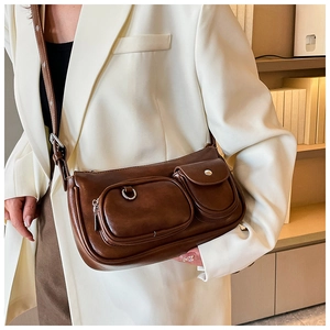 Detail of a vintage dark brown shoulder bag featuring two front pockets and silver hardware