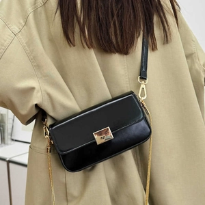 Minimalist black square crossbody bag with gold buckle on a beige trench coat