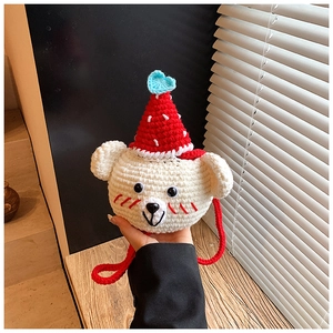 Close-up of handmade crochet bear bag showing intricate knit texture and strawberry hat