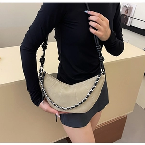 Sac croissant matelassé beige avec chaîne argentée et bandoulière noire à nœuds