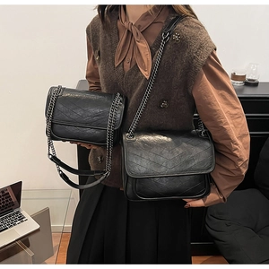 Comparison of two sizes of black chevron quilted chain bags in a modern office setting