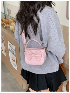 Pink girl's crossbody bag with bow and crocodile texture in a cozy cafe setting