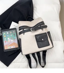 Detail of color-block backpack showing faux leather straps and metal buckle closure