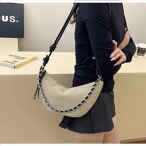 Détail du sac croissant beige avec texture matelassée et bandoulière noire nouée