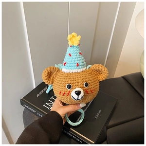 Macro view of handmade crochet bear coin purse with party hat on a designer book