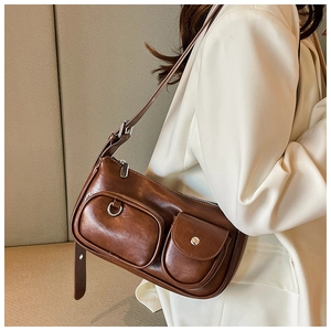 Detail of retro brown shoulder bag featuring dual front pockets and silver hardware