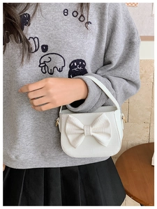 Detail of white PU leather kids handbag featuring crocodile pattern and large bow