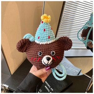 Detail of a handmade brown crochet bear bag with a blue party hat and knit strap