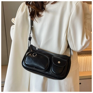Detail of black stylish shoulder bag with silver zippers worn over a white blazer