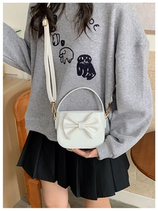 Close-up of white crocodile pattern PU leather bag with large bow and crossbody strap