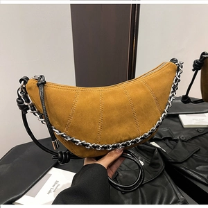 Detail of mustard yellow suede croissant bag with quilted design and silver chain strap