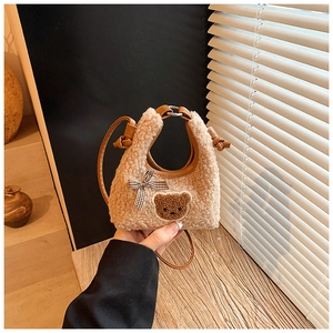Détail du sac peluche ours avec nœud à carreaux et texture polaire douce