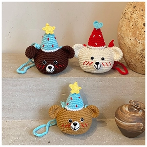 Detail of three handmade crochet bear mini bags with pointed hats and colorful lanyards