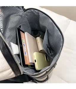 Interior view of large capacity white leather backpack showing striped lining and pockets