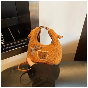 Vue détaillée du sac en peluche marron avec écusson d'ours, nœud et poignée ronde