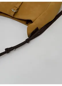 Détail de la bandoulière réglable avec boucle en métal argenté sur un sac cabas jaune