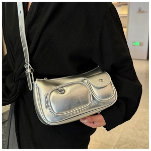 Detail of silver metallic crossbody bag with multi-pocket design on black top background