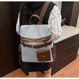 Detail of blue denim backpack with brown leather trim and retro decorative buckle