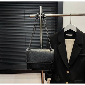 Detail of black chevron quilted shoulder bag with dark metal chain strap on display