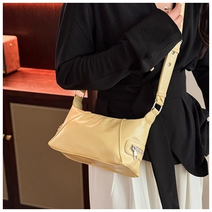 Detail of light yellow soft leather tote bag featuring side zipper and adjustable strap
