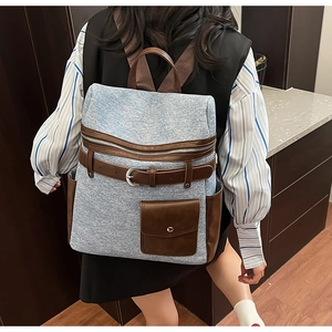 Detail of blue denim backpack with brown leather patchwork and vintage metal buckles