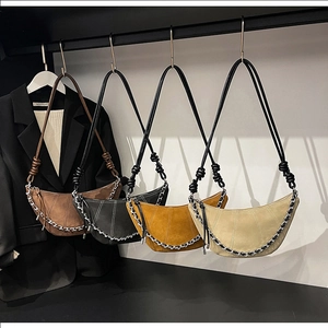Detail of four suede crescent bags featuring metal chains and unique knotted shoulder straps