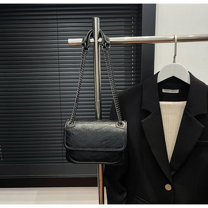 Detail of black chevron quilted shoulder bag with dark grey metal chain strap