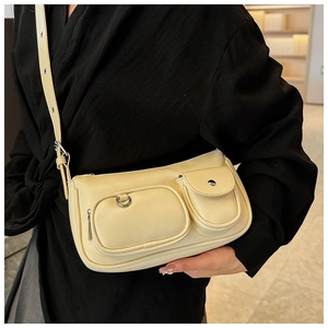 Detail of cream PU underarm bag featuring functional front pockets and adjustable strap