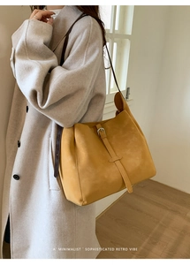 Détail du grand sac seau en cuir jaune moutarde avec bandoulière marron et boucle
