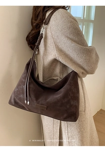 Detail of dark brown retro tote bag with suede texture and metal chain strap