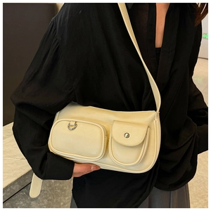 Detail of beige shoulder bag with double front pockets and wide leather strap on model