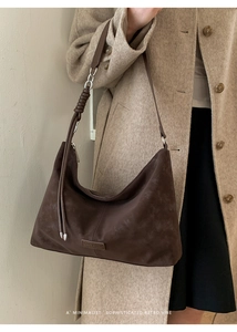 Detail of dark brown suede hobo bag featuring a unique knotted shoulder strap design