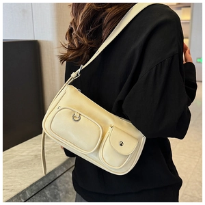 Detail of beige multi-pocket underarm bag showing matte leather texture and silver hardware