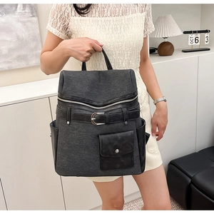 Detail of grey fabric backpack with black leather straps and large decorative buckle