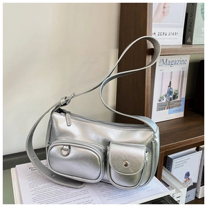 Detailed view of silver metallic bag with two front pockets on a wooden shelf