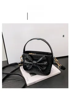 Detail of black croc-effect girls' handbag featuring a large bow and gold hardware
