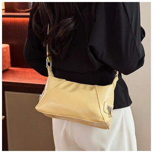 Detail view of cream yellow PU leather shoulder bag with fine stitching and silver hardware