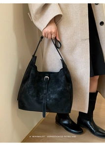 Détail du sac cabas en daim noir avec boucle argentée et texture rétro minimaliste