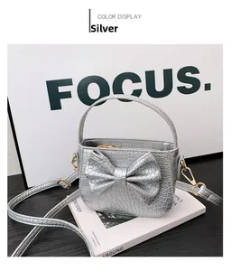 Detailed close-up of a silver crocodile pattern mini handbag with a large decorative bow