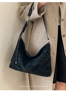 Detail of black suede hobo bag featuring thick braided shoulder strap and brand logo