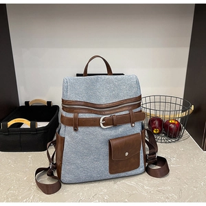Detail of blue canvas backpack with brown leather strap and front pocket buckle
