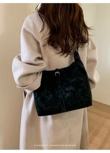 Détail d'un sac cabas noir minimaliste montrant la texture suédée et la boucle en métal
