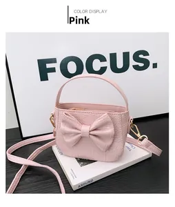 Detail of pink faux crocodile leather texture and bow decoration on child handbag