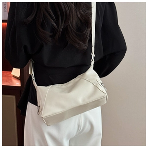 Detail of off-white PU leather crossbody bag with smooth texture and silver metal zippers