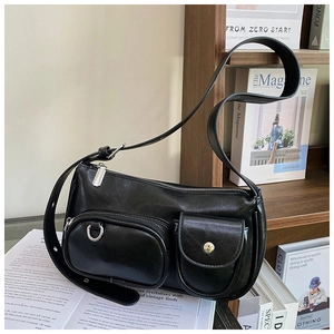 Detail of black multi-pocket shoulder bag with silver D-rings and retro utility style